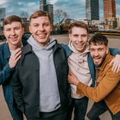 Four members of The Lilacs stood in an empty car park with high rise flats in the background